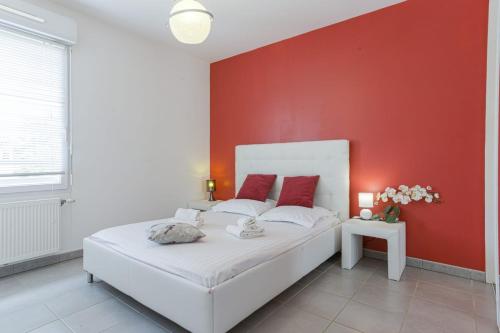 une chambre avec un lit blanc avec un mur rouge dans l'établissement Appartement Pigue - Welkeys, à Labenne