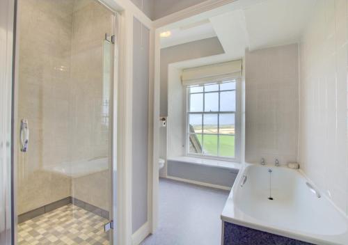 uma casa de banho com uma banheira, um chuveiro e um lavatório. em Carnevas Farmhouse em Saint Merryn