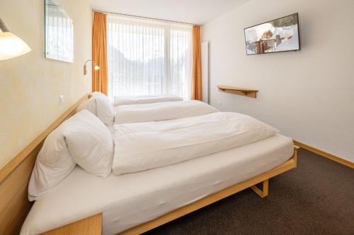 two beds in a room with a window at Aktiv Hotel & Spa Hannigalp in Grächen