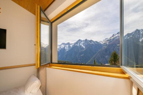 a room with a window with a view of mountains at Aktiv Hotel & Spa Hannigalp in Grächen