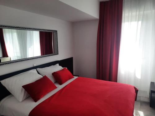 a bedroom with a red and white bed with a mirror at Hotel Prunk in Sežana