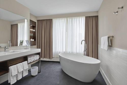 La salle de bains est pourvue d'une grande baignoire blanche et d'un lavabo. dans l'établissement Delta Hotels by Marriott Edmonton Centre Suites, à Edmonton