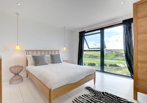 a bedroom with a bed and a large window at Pen Y Mor in Mawgan Porth