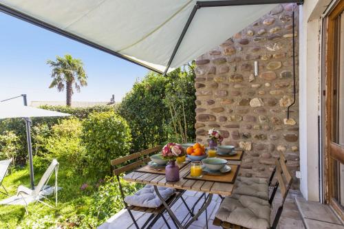 - une table et des chaises sur une terrasse avec un parasol dans l'établissement Maison Lamina - Welkeys, à Anglet