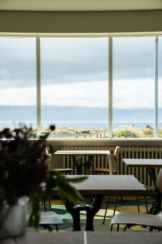 a room with tables and chairs and a large window at Hótel Blönduós in Blönduós