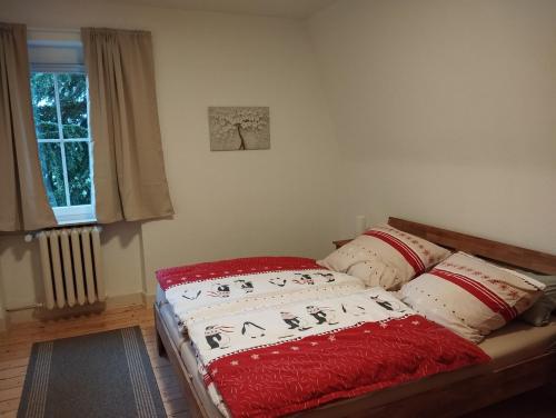 uma cama num quarto com um cobertor vermelho e almofadas em Ferienwohnung Gasthof Port em Naunheim
