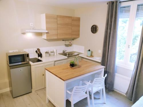 une cuisine avec des placards blancs et un comptoir avec des chaises dans l'établissement Baiona Sainte Cath 3-HIRU cœur de Saint Esprit, à Bayonne