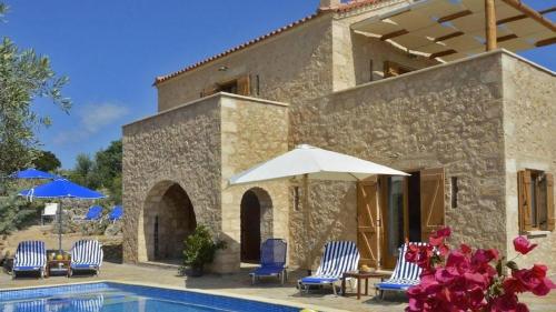 a house with chairs and umbrellas next to a swimming pool at Villa Amalthiea in Arménoi