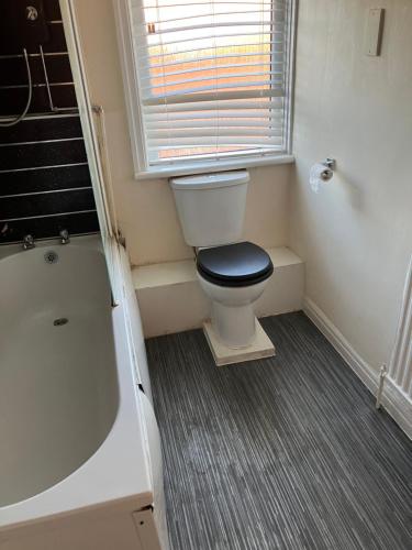a bathroom with a toilet and a bath tub at Astley House - Manchester in Dukinfield
