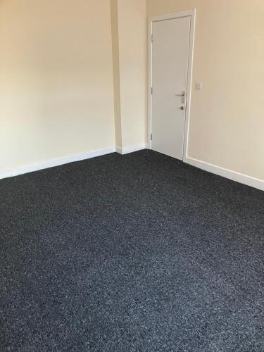an empty room with a door and carpet at Astley House - Manchester in Dukinfield