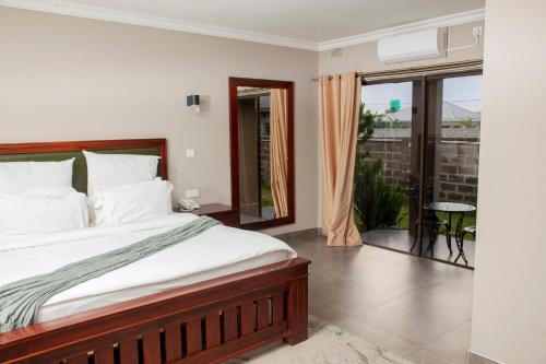 a bedroom with a bed and a balcony at Unji Lodge in Ndola