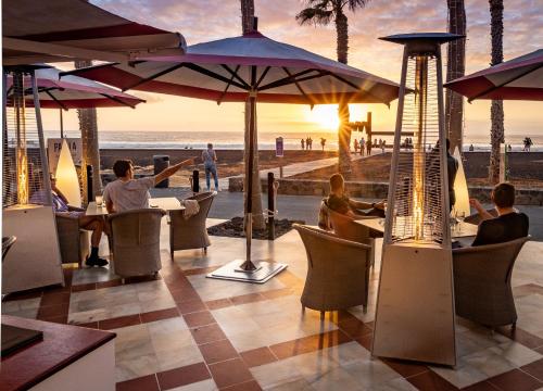 a restaurant at the beach with people sitting at tables at Parque Santiago IV Official in Playa de las Americas