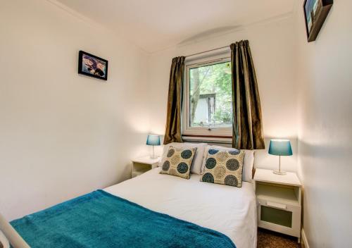 een slaapkamer met een bed, 2 lampen en een raam bij Breakaway Lodge in Carbis Bay