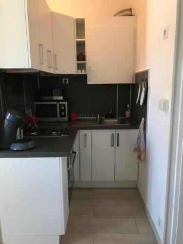 une petite cuisine avec des armoires blanches et un micro-ondes dans l'établissement Appart clim et parking - entrée quartier naturiste, au Cap d'Agde
