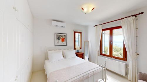 a white bedroom with a bed and a window at Villa Zeitouni in Nisakion