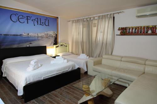 a hotel room with two beds and a couch at Madema B&B in Cefalù