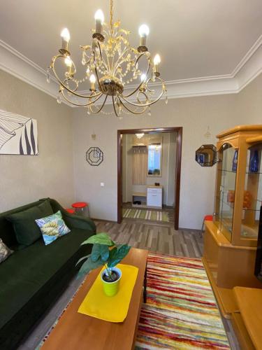 een woonkamer met een groene bank en een kroonluchter bij Квартира возле оперного театра 22 in Alma-Ata