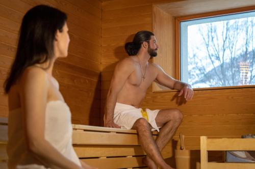 a man and a woman sitting in a sauna at Aktiv Hotel & Spa Hannigalp in Grächen