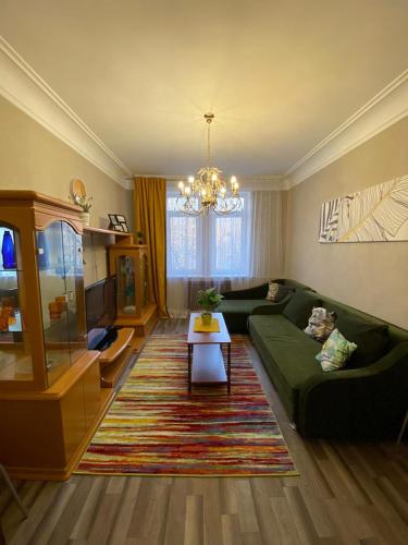 een woonkamer met een groene bank en een tafel bij Квартира возле оперного театра 22 in Alma-Ata