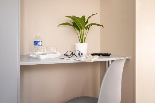 a white table with a plant and glasses on it at Hôtel de Lion sur Mer in Lion-sur-Mer
