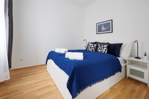 ein weißes Schlafzimmer mit einer blauen Decke auf einem Bett in der Unterkunft Charming Apartment near Center in Wien