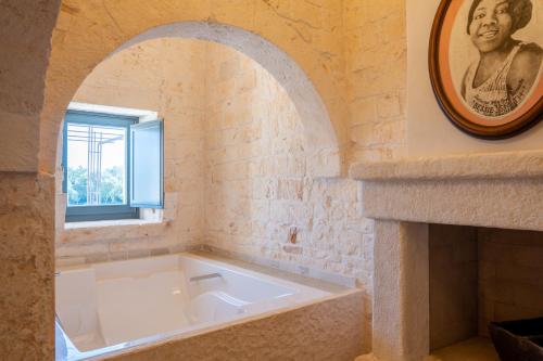 uma banheira branca num quarto com uma janela em Masseria Santo Scalone em Ostuni