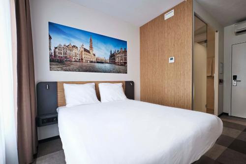 ブリュッセルにあるイージーホテル ブリュッセル シティ センターの白いベッドと壁に絵画が飾られたベッドルーム1室
