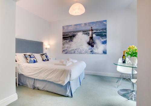 a bedroom with a bed and a picture of a lighthouse at Aquarius in Saint Levan