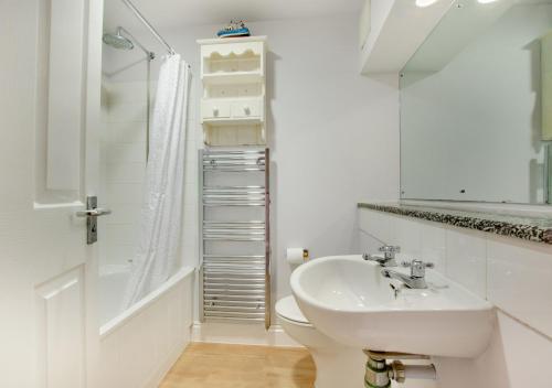 a white bathroom with a sink and a shower at Aquarius in Saint Levan