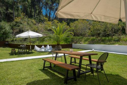 a picnic table and chairs under an umbrella at Sunset Villas in Possidi