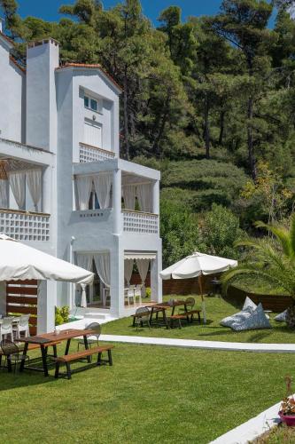 a white building with picnic tables and umbrellas at Sunset Villas in Possidi