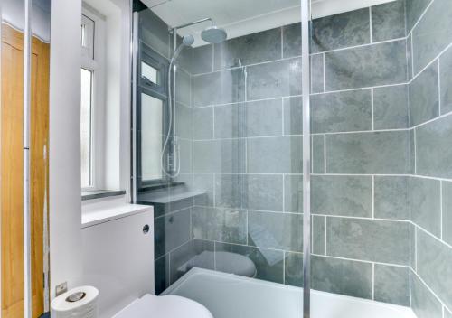 a bathroom with a shower with a toilet and a sink at Neptune House in Porthleven