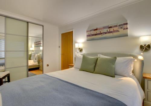 a bedroom with a large white bed with green pillows at Neptune House in Porthleven