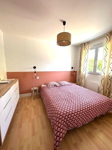 une chambre avec un grand lit avec une couette rouge dans l'établissement La Maison Cilaos - Proche mer, à Les Sables-dʼOlonne