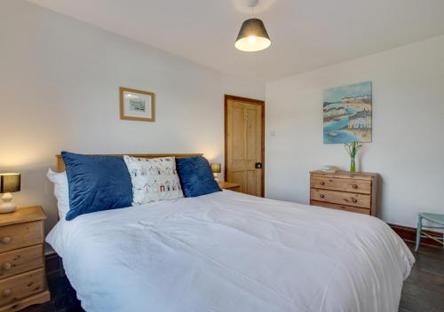 a bedroom with a large white bed with blue pillows at Auntie Katies Cottage in Looe