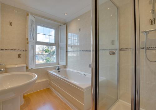 a bathroom with a tub and a sink and a shower at Auntie Katies Cottage in Looe