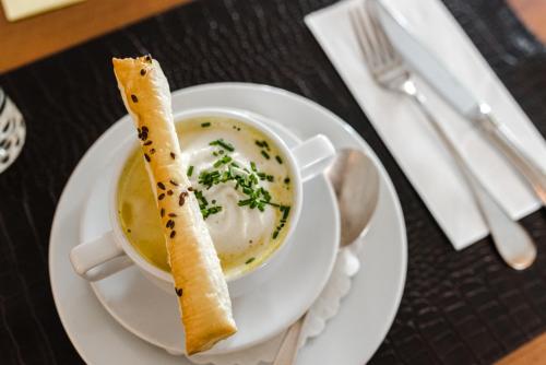 a white plate with a bowl of soup and a piece of bread at Aktiv Hotel & Spa Hannigalp in Grächen