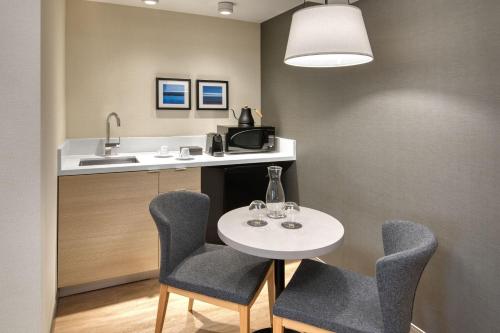 a kitchen with a table and two chairs and a sink at The Insignia Hotel, Sarnia, a Tribute Portfolio Hotel in Sarnia