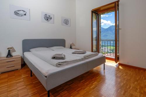 a bedroom with a bed and a large window at Palm Cottage in Locarno