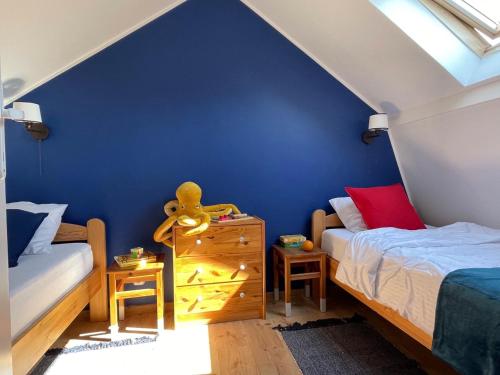 a bedroom with two beds and a blue wall at Klara w Ogrodzie in Łeba