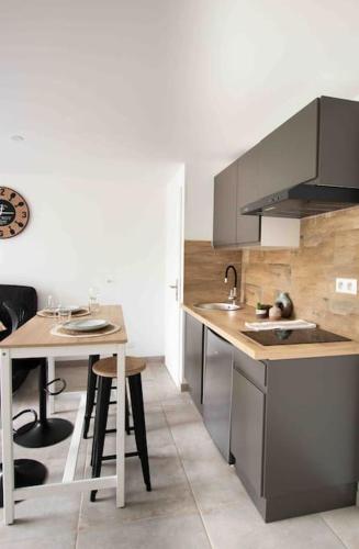- une cuisine avec un évier et une table avec des tabourets dans l'établissement Apt T2 neuf terrasse, à Arles