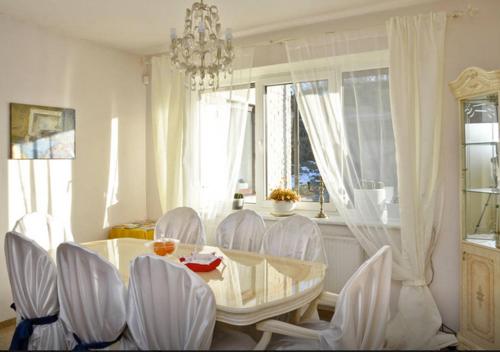 a dining room table with white chairs and a chandelier at Irena Family House in Vilnius