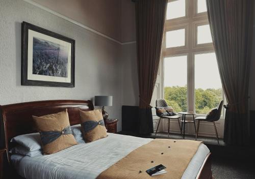 a bedroom with a bed and a large window at Cave Castle Hotel in South Cave