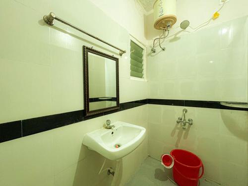a white bathroom with a sink and a mirror at Paradise Elite Rooms in Madurai