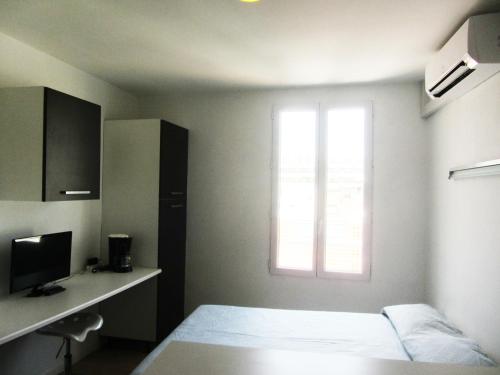 une petite chambre avec un lit et une fenêtre dans l'établissement Studios Belges, à Cannes
