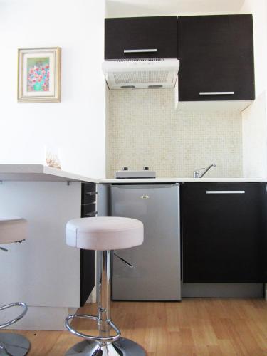 une cuisine avec des placards noirs et blancs et un tabouret dans l'établissement Studios Belges, à Cannes
