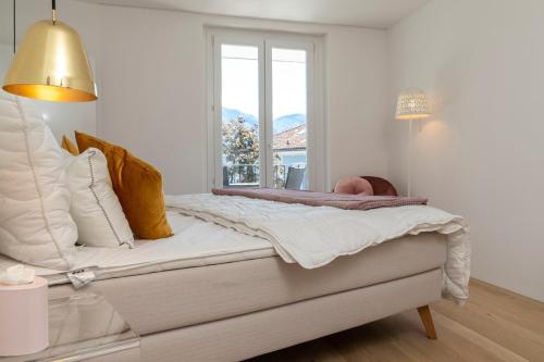 a white bedroom with a bed with a window at Orselina in Style in Orselina