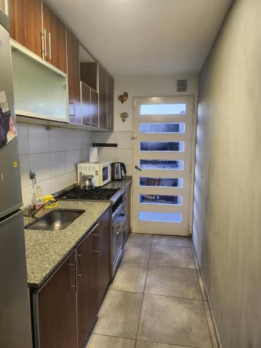 una pequeña cocina con fregadero y nevera. en Departamentos Dany en Buenos Aires