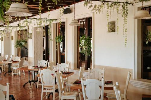 a restaurant with tables and white chairs and plants at Parador Nature Resort and Spa in Manuel Antonio