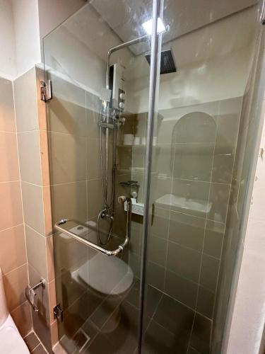 a shower with a glass door in a bathroom at Coast Residences Penthouse with skyline and manila bay view in Manila